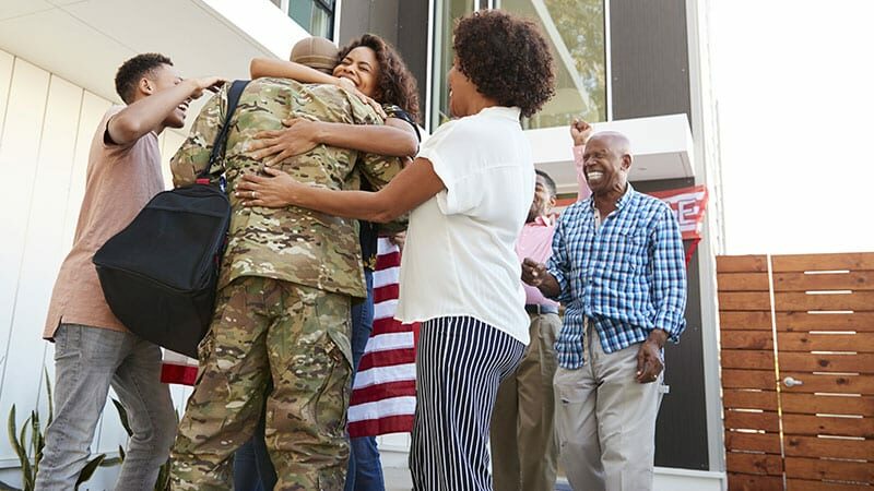 family welcoming soldier home with hugs